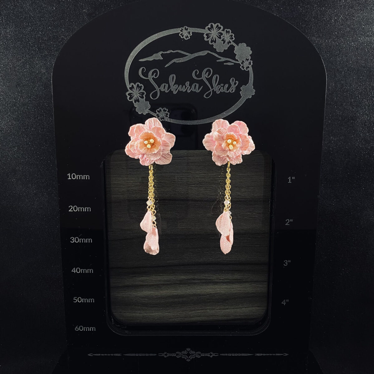 Pink blossom earrings made out of polymer clay with three gold chains ending in clay petals.