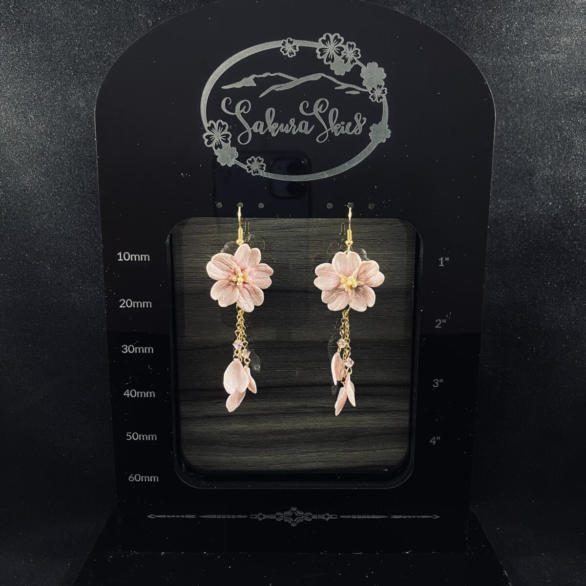 Pink blossom earrings made out of polymer clay with three gold chains ending in clay petals.